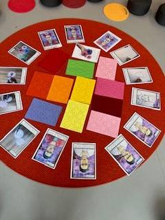 eine rote kreisförmige matte mit bunten, strukturierten karten und mehreren karten mit abbildungen von frida kahlo, die in einem kreis auf einem grauen boden angeordnet sind.